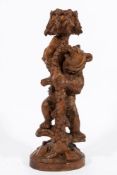 A Black Forest carved linden wood pedestal stand: in the form of a bear climbing a fir tree,