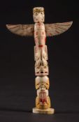 An American North Westcoast marine ivory miniature totem pole: carved and stained with stylised