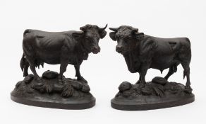 A pair of Swiss Black Forest carved linden wood models of a cow and bull: on oval naturalistic