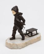 An Art Deco period bronze and ivory study of a boy pulling a sledge: with inset carved ivory face,