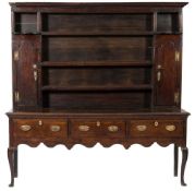 An 18th century and later oak dresser:, the shelved superstructure with a moulded cornice,