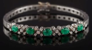 An emerald and diamond mounted bracelet: with five oval emeralds separated by cinquefoil clusters