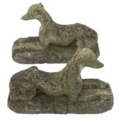 A pair of carved reconstituted stone figures:, of recumbent dogs, 66cm (2ft 2in) long.