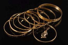 A textured bracelet stamped '750' together with seven various bangles and a nugget pendant stamped