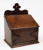 A 19th century oak candle box: the shaped backplate with sloping hinged lid and moulded geometric