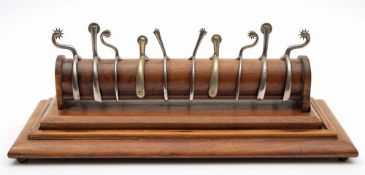 A collection of five sets of Victorian silver plated spurs on a mahogany rack:,