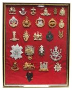 A framed group of various regimental cap and collar badges:.