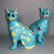 A pair of Mosanic pottery cats: in seated posture with curled tail with inset glass eyes,
