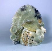 An Oriental carved hardstone reticulated figure of a displaying peacock: the stone of mottled