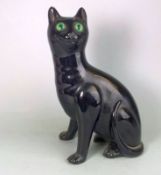 A Bretby pottery cat: modelled in seated posture with curled tail and inset glass eyes under a jet