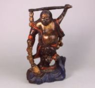 A Chinese decorated lacquer and carved wood figure: of a corpulent man dancing above waves and