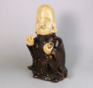 A Japanese brown glazed stoneware figure of Fukurokuju: the smiling god holding a scroll in his