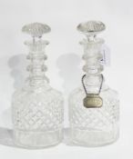 Two cut glass mallet-shaped decanters with triple ring necks, one having silver label 