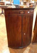 A Georgian mahogany bowfront corner cupboard with inlaid satinwood frieze,