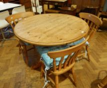 A pine circular top dining table with turned baluster support on quadruped splayed legs,
