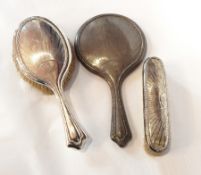 A George V silver-backed dressing table set comprising hand mirror, hairbrush and clothes brush,