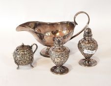 A pair of pepperettes, repousse design with blank cartouche on circular foot,