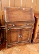 An oak bureau with one long frieze drawer and two cupboards, fitted interior,