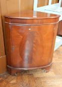 A mahogany corner cabinet with concealed shelf,