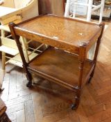 A mahogany two-tiered tea trolley on cylindrical and block supports, wheels,