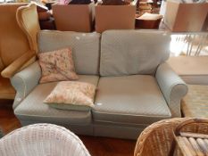 A two-seater sofa with green patterned upholstery covers