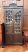 An oak display cabinet with scroll carved cornice,