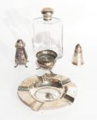 A circular silver ashtray, marks rubbed, a silver capped glass bottle,