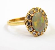A gold, opal and diamond cluster ring, the central oval opal surrounded by 12 eight-cut diamonds,