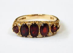 A 9ct gold, garnet and diamond ring set five graduated oval garnets,