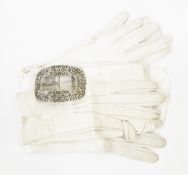 A continental silver-coloured metal buckle with a metal stamp and two pairs of cream kid leather