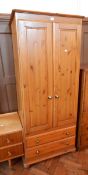 A modern pine single wardrobe, the pair of panelled doors enclosing hanging space,