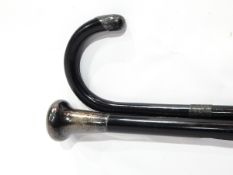An ebonised walking stick with silver finial and another cane with silver mounts