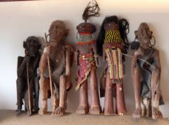 Three carved African wooden figures of seated men with earrings and two African naive carved