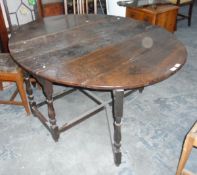 An antique oval oak fall-flap gateleg table on turned supports