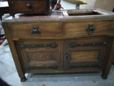 An oak sideboard with tiled top and raised backpiece, on square tapering legs,