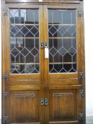 A reproduction glass fronted display cabinet with four shelves and cupboard, linenfold decoration,