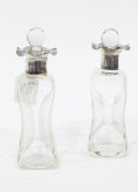 A pair of glass scent bottles of waisted form, with silver collars,