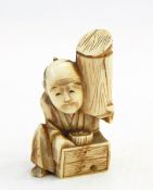 Japanese carved ivory netsuke, man seated and holding a cylinder,