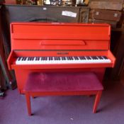 A Cramer upright piano with red lacquered finish.