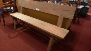 A rustic vintage oak bench of elongated form with plank back and seat raised on stretchered