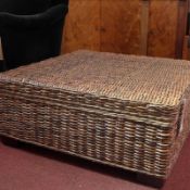 A wicker Ottoman of square form on bun feet.