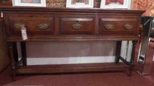 An 18th century oak dresser base fitted three drawers with oval brass plate handles and raised on