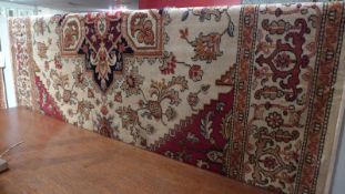 A Heriz style rug the beige field having central medallion and geometric motifs in a multi border.