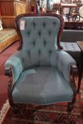 A Victorian Mahogany armchair upholstered in blue buttoned fabric supports and castors.