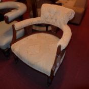 An Edwardian walnut ladies chair upholstered in gold buttoned fabric and raised on turned supports