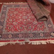 A Persian carpet, the red ground having extensive foliate motifs in a blue border.