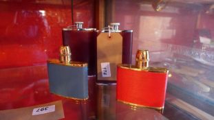 A collection of four various leather clad hip flasks.