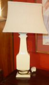 A cream painted bedside table with brushing slide and single drawer, and two lamps.