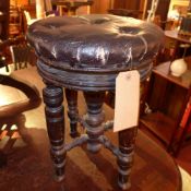 A Victorian adjustable piano stool with faux leather upholstery and raised on turned stretchered