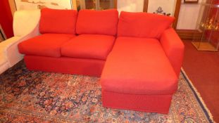 A red upholstered corner sofa of sectioned construction on bun feet.